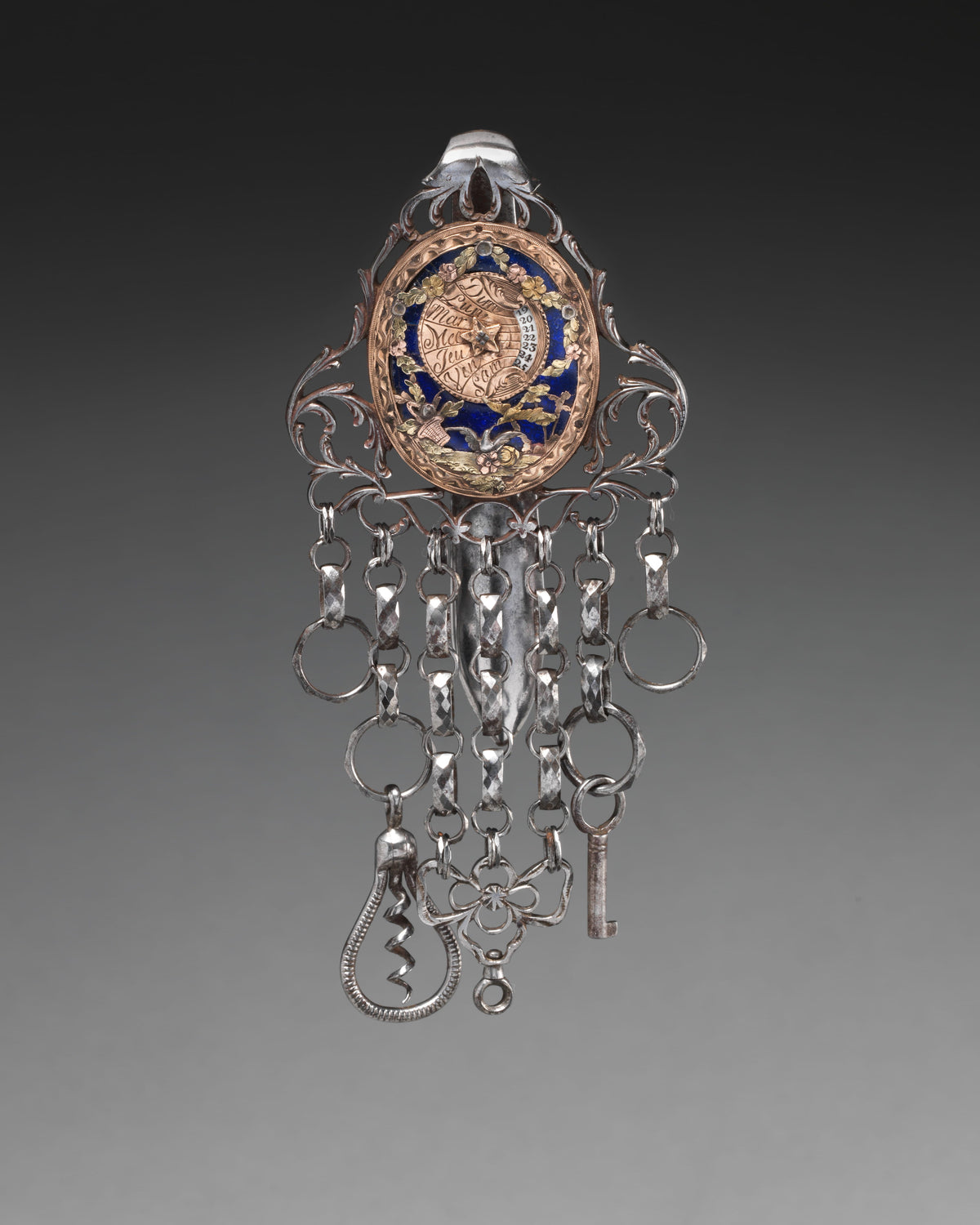Steel chatelaine with an enamelled gold calendar plaque and multiple suspension chains